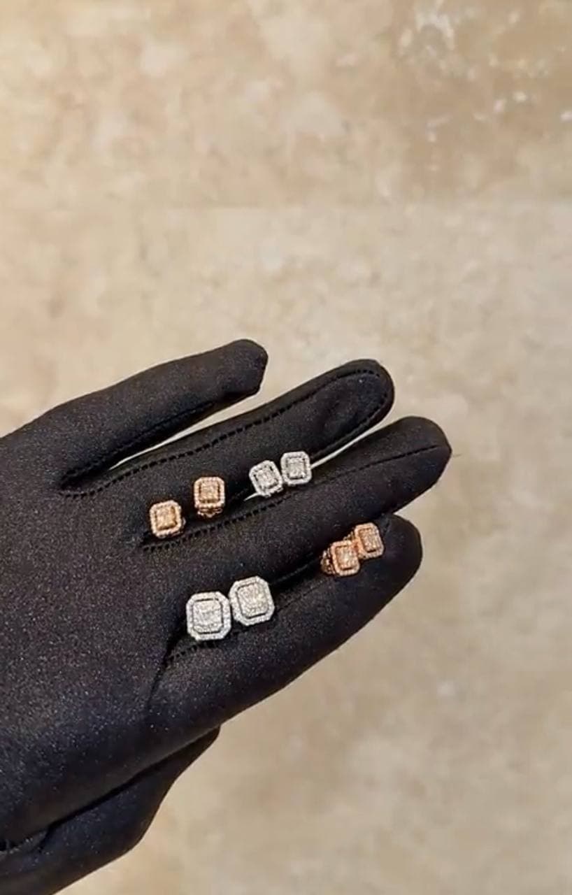 Diamond earrings arranged on a black presentation glove.