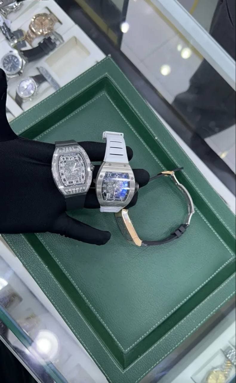 Two diamond timepieces presented on a black glove.