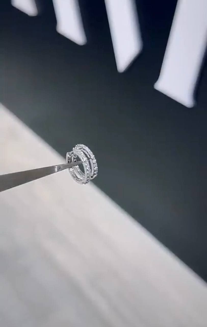 A diamond ring examined with tweezers in a private showroom setting.